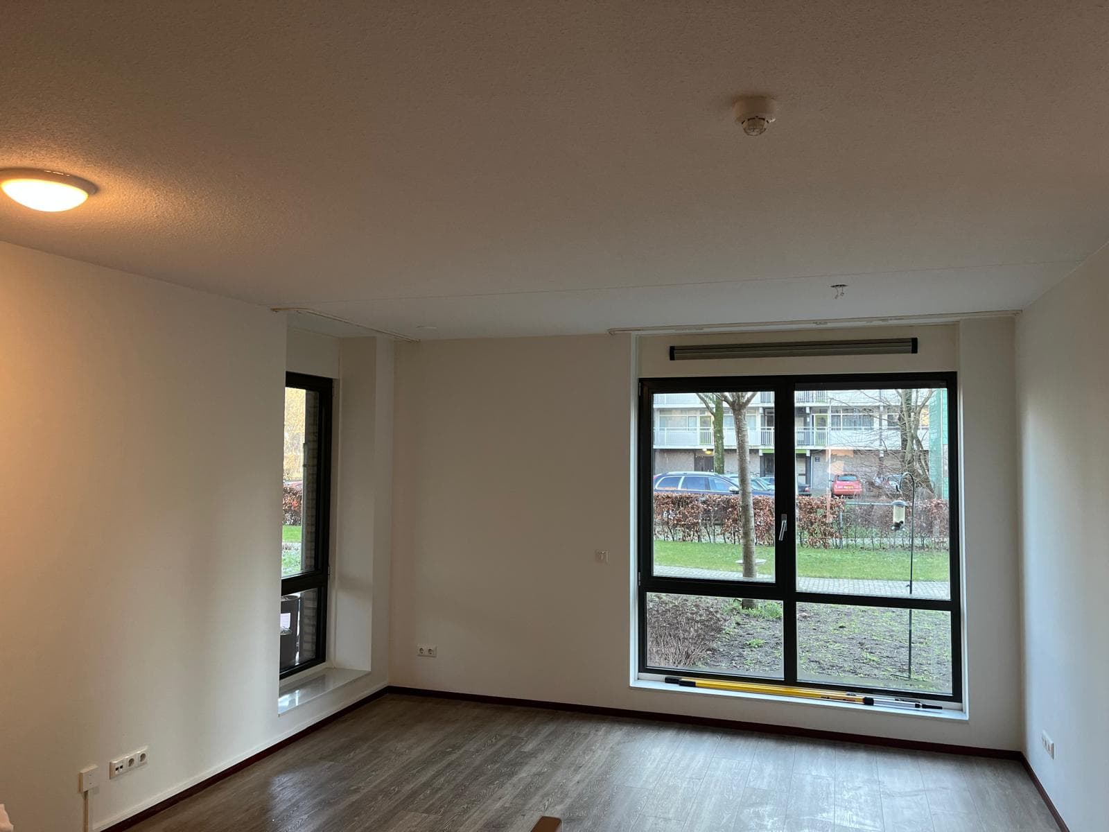 Woonkamer met wit geschilderde wanden en plafond en een grote raampartij