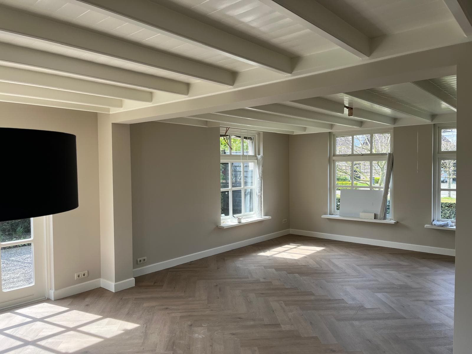 Woonkamer met wit geschilderd balkenplafond, wanden en kozijnen