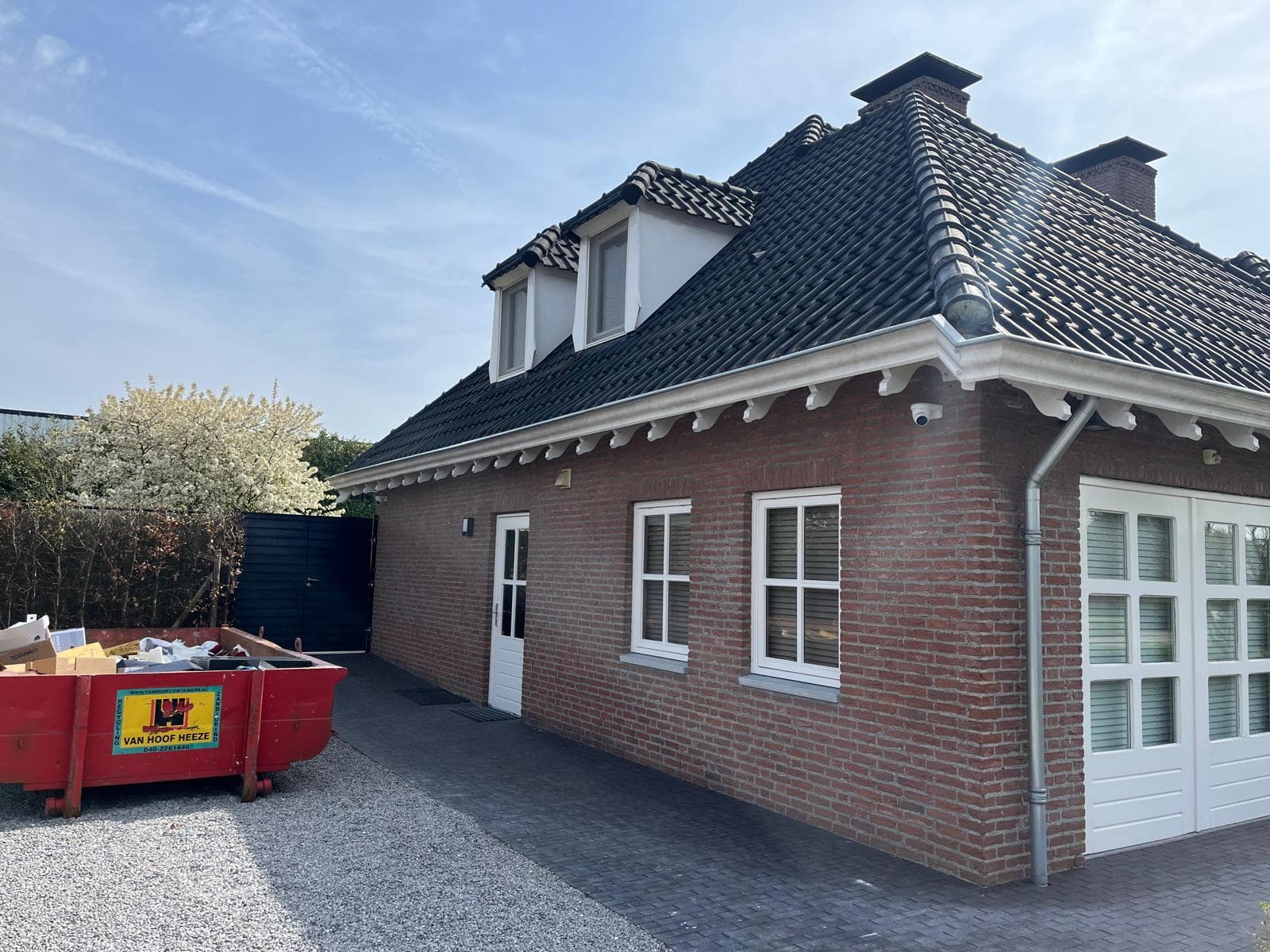 Zijgevel met wit geschilderde kozijnen, garagedeuren en gootlijst